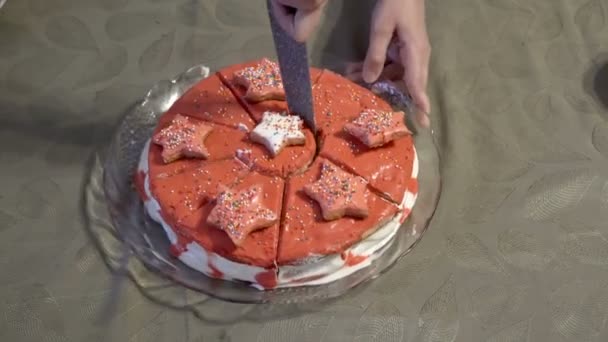 Una mujer corta una estrella-decoración del medio de una torta hermosa con un cuchillo de cocina grande. El pastel casero está decorado con crema, chocolate rojo y estrellas. Primer plano. Sin rostro. Vista superior. 4K — Vídeo de stock