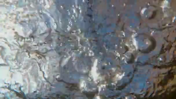 Een ongewoon uitzicht van onder het water op het oppervlak van een snelle rivier waarop bubbels snel tegen de blauwe lucht zweven. Een abstractie. Hypnose herhalend patroon van golven. Surrealistisch realisme. 4K — Stockvideo