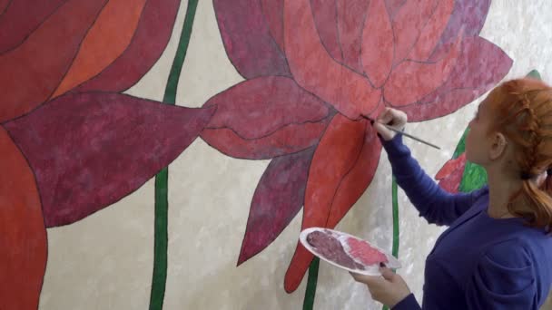 Genç ve güzel bir kız odasındaki duvar kağıdına harika çiçekler çiziyor. Ev yaratıcılığı kavramı. Yakın plan. Yan görüş. 4K — Stok video