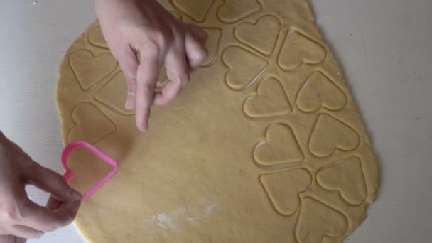 Detailní záběr, ženské ruce vystřižené ze syrových těsta polotovarů pro sušenky ve tvaru srdce. V kuchyni vaří žena. Koncept malého domácího podniku. Bez tváře. Horní pohled. 4K — Stock video