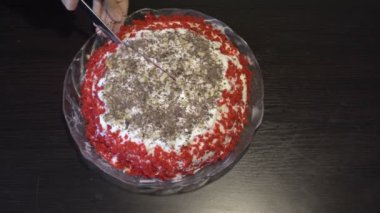 Kadın, siyah bir masanın üzerindeki cam bir tabağın üzerinde duran beyaz kremalı güzel bir kırmızı pastayı parçalara ayırmaya başlar. Yakın plan. Üst Manzara. Yüzsüz. Uzayı kopyala 4K.
