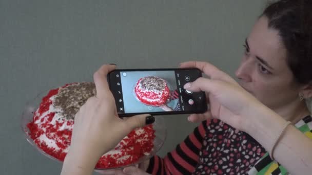 Anne ve kızı akıllı bir telefondan resim çekiyor. Evde yapılan güzel bir kırmızı pasta. Karantina sırasında ev işi kavramı. Yakın plan. Arkadan üstten bak. 4K. — Stok video