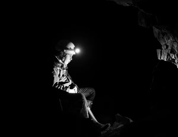 Girl resting in an abandoned mine with light from head torch — Stock Photo, Image