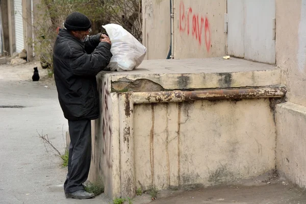 Homeless man looking for food in rubbish in Baku, capital of Azerbaijan — Stock Photo, Image