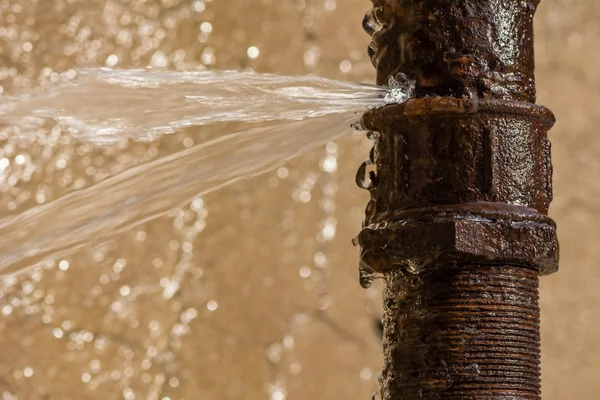 Roestige burst pijp sproeien van water — Stockfoto