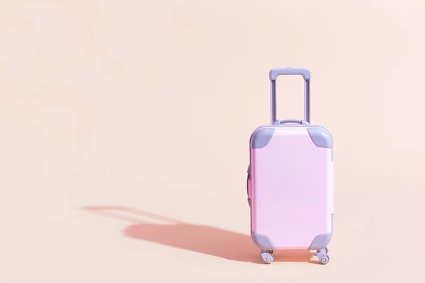 Pink Suitcase speelgoed op een perzik, zandige achtergrond. Minimalisme en reisconcept — Stockfoto