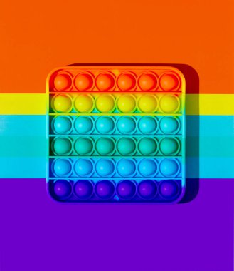 Stres önleyici dokunmatik pop, gökkuşağı arka planında bir oyuncaktır. Makro resim, gölge