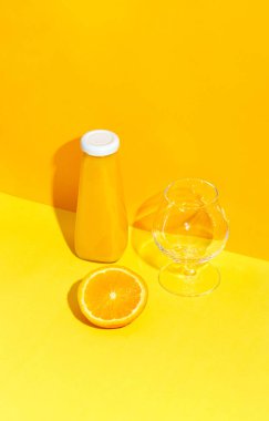 Portakal suyu, taze portakal ve boş bardakla dolu bir şişe..
