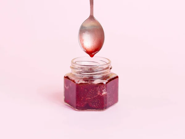 小さなガラス瓶にスプーンから滴下ラズベリージャム. — ストック写真