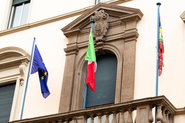 Padova, İtalya - 14 Nisan 2025: Avrupa Birliği ve İtalyan bayrakları karmaşık taş işçiliği ve balkonla tarihi binada sergilenerek, kültürel gurur vurgulandı