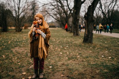 Parkta poz veren genç bir kız oyuncağı kucaklıyor.