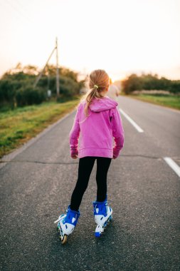 Pembe kapüşonlu, siyah pantolonlu, uzun sarı saçlı, köyün yolunda paten giyen güzel beyaz kız.