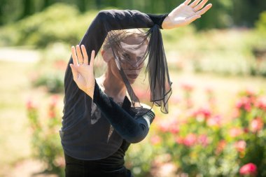 Siyah, eski moda elbiseli ve parkta poz veren güzel bir kız.