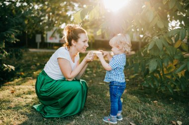Genç, beyaz bir anne ve küçük sarışın oğlu parkta birlikte vakit geçiriyorlar..