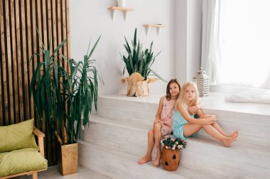 Neşeli yüz ifadeleri olan iki neşeli kadın çocuk beyaz iç stüdyoda dekorasyonlarla sarılıp poz veriyorlar..