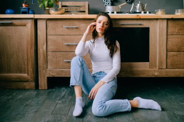 Şehvetli bir yüzü, mutfakta poz veren uzun siyah saçları olan sevimli genç bir manken. İç mekan hayat tarzı, neşeli, şefkatli, İspanyol görünümlü ve kameraya bakan kahverengi gözlü bir kızın portresi. 