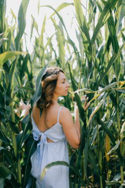 Kısa siyah dalgalı saçlı, açık mavi yazlık elbiseli çekici beyaz kadın portresi hafta sonları mısır tarlasında sükunetini koruyor..