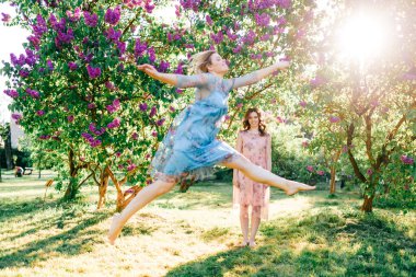 Elbiseli güzel, şık kızlar yaz günü açık havada leylak çiçeklerinin açtığı bahçede eğleniyorlar. Neşeli kahkahalar atan mutlu bale dansçıları doğada eğitim görüyor. Spor aktivitesi. Dans atlayışları