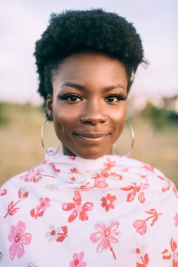 Güzel esmer tenli kız şık bir elbise giyip açık havada moda portresi yapıyor. 