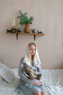 Dekoratif arka planda oyuncak ayıyla sarmalanmış tuhaf beyaz kız.