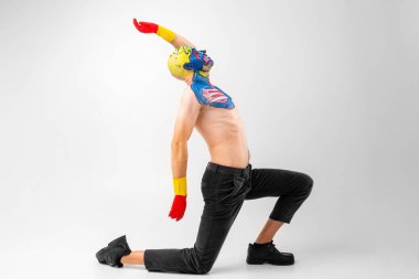 Kafasında ve omzunda beyaz tişört, kırmızı ve sarı eldivenler ve kırmızı danslar olan garip bir adam.