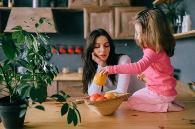 Sevimli genç bayan mutfakta komik kızıyla oynuyor. Güzel bir annenin portresi kucağında taşıdığı ve küçük dişi çocuğunu izlediği. Mutlu aile içinde yaşam tarzı portresi.