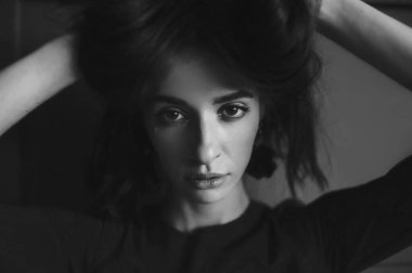 Koyu renk uzun saçlı, İspanyol görünümlü ve stüdyoda poz veren kırmızı elbiseli güzel bir moda kızı. Kapalı kapılar ardında siyah-beyaz, koyu renk gözlü harika esmer kadının portresi..