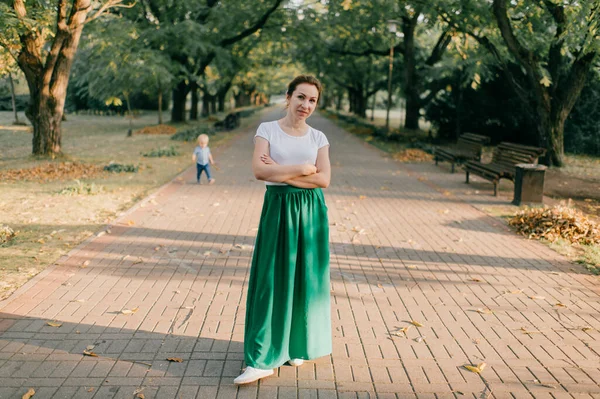 一个穿着白色T恤衫和绿色长裙的年轻漂亮的姑娘在一个轻便的公园里散步 — 图库照片