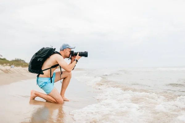 Człowiek Aparatem Fotograficznym Robi Zdjęcia Morza Mężczyzna Fotograf Siedzi Plaży — Zdjęcie stockowe