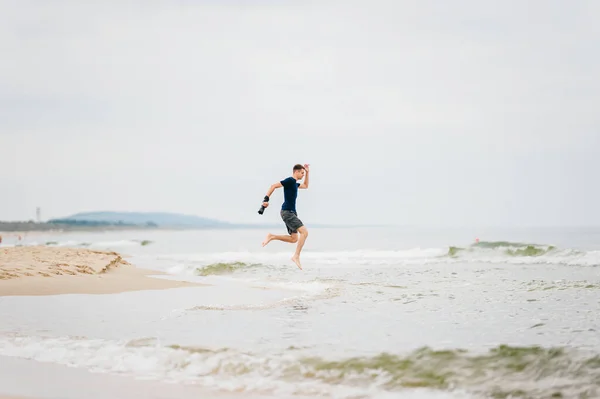 사진술자는 모래가 해변에서 곳으로 뛰어오르며 경치를 즐긴다 카메라를 해변으로 뛰어드는 — 스톡 사진