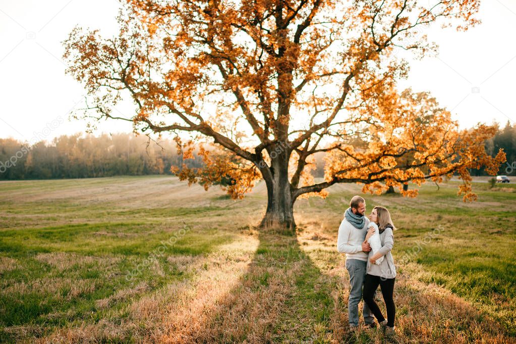 Loving couple with funny pet in field at sunset.