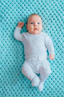 Mavi gözlü, sevimli, yeni doğmuş erkek bebek. İçeriden çekilmiş bir portresi var. Beyaz pijamayla turkuaz yün ekose üzerinde tombul yanaklı şirin bir çocuk. Komik hemşire çocuk duyguları..