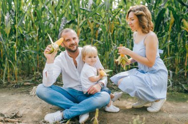Açık mavi elbiseli genç, beyaz gömlekli, kısa siyah saçlı beyaz saçlı, beyaz pantolonlu, beyaz elbiseli güzel anne, küçük bebekleriyle çok eğleniyorlar.