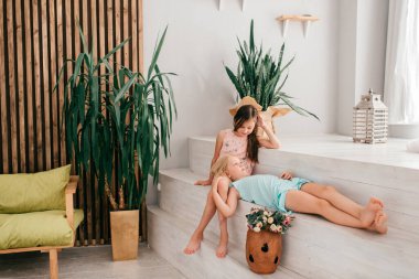 Neşeli yüz ifadeleri olan iki neşeli kadın çocuk beyaz iç stüdyoda dekorasyonlarla sarılıp poz veriyorlar..