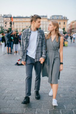 Krakow 'un ana meydanında gülümseyen ve yürüyen mutlu çift.)