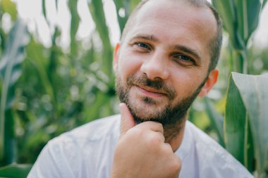 Beyaz gömlekli, kot pantolonlu ve beyaz çizmeli güzel beyaz bir adam mısır tarlasında yürüyüşe çıkıyor..