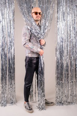 Parlak beyaz gömlekli, siyah deri pantolonlu, gri ayakkabılı ve parlak gümüş renkli gözlüklü tuhaf beyaz adam..