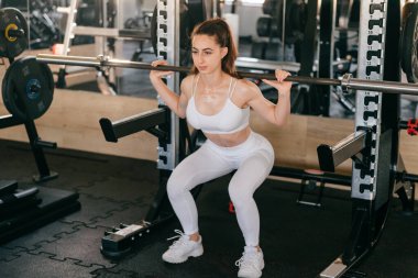 Genç bir atletik kız spor aletlerini kullanarak spor yapıyor.