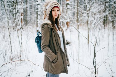 Kar ormanında poz veren eşarplı genç ve çekici bir kız.