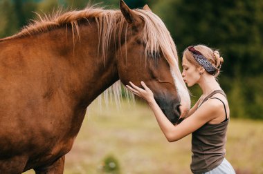 Genç güzel kız doğada ata sarılıyor..