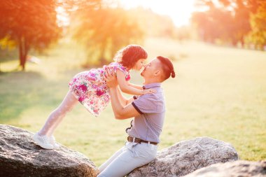 Baba ve kızı yaz açık hava aktiviteleri. Sevgi dolu baba, sevimli neşeli bebeğine tapar. Ebeveyn ve çocuk parkta eğleniyor. Küçük kız babasına doğru düşüyor. Mutlu aile portresi