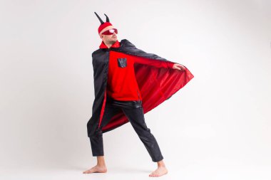 Siyah cadılar bayramı kostümü içindeki zarif adam ve beyaz stüdyo arka planında egzantrik bir aktör gibi poz veren şeytan boynuzları..