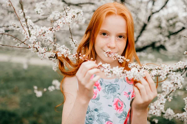 Выразительная Девушка Длинными Рыжими Волосами Бледной Кожей Нюхает Цветы Цветущих — стоковое фото