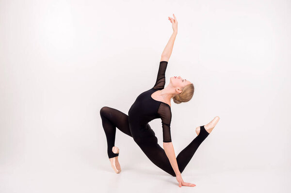 Young caucasian girl with long fair hair, pretty face in black swimsuit and white skirt for ballet engaged art gymnastic