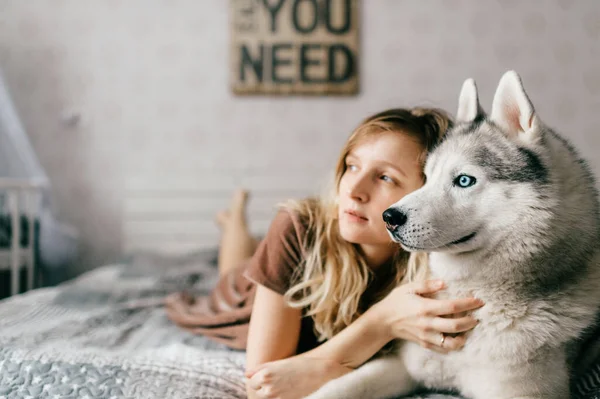 Młoda Dziewczyna Brązowej Sukience Leżąca Łóżku Domu Sypiająca Husky Szczeniakiem — Zdjęcie stockowe