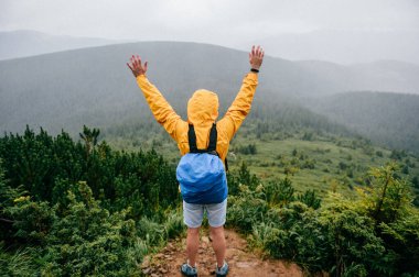 Dağın tepesinde duran mutlu adam. Gezgin doğa manzarasının tadını çıkarıyor.