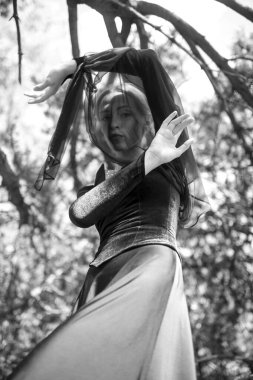 Siyah, klasik elbiseli, ağaçların arasında poz veren güzel, zarif bir kız..