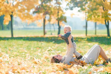 Genç anne güneşli bir günde doğada sevimli çocuğuyla eğleniyor..