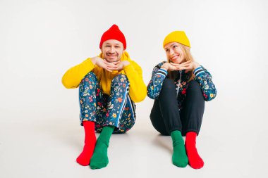 Beyaz arka planda renkli kıyafetler giymiş şık bir çift.