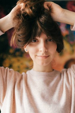 Kameraya poz veren güzel esmer bir kızın kapalı mekan hayat tarzı portresi..